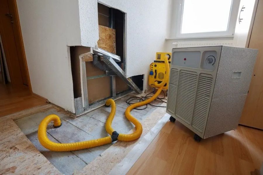 Air movers and a dehumidifier running inside a room during structural drying